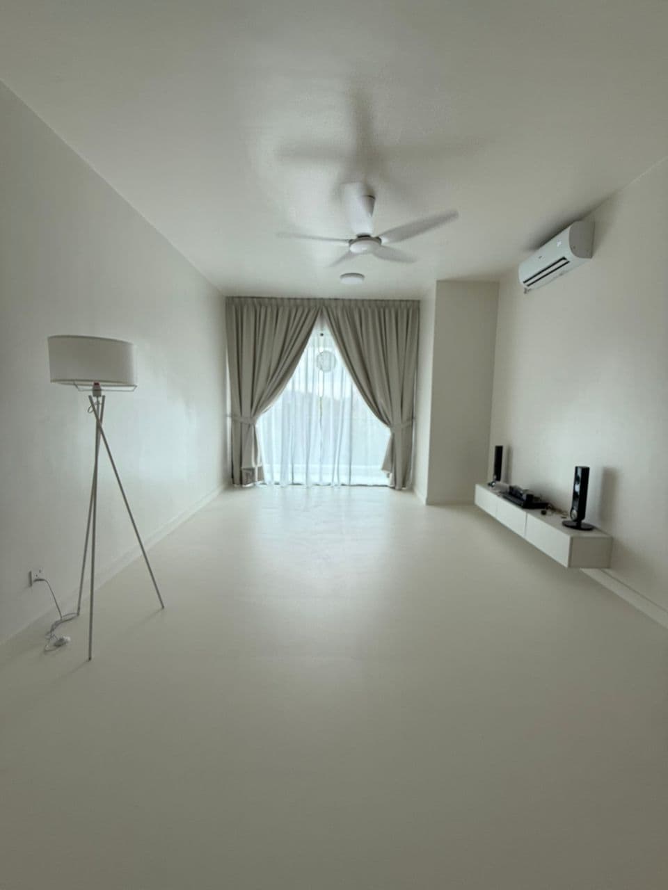 Minimalist white room with a tripod floor lamp, ceiling fan, and floating media console.