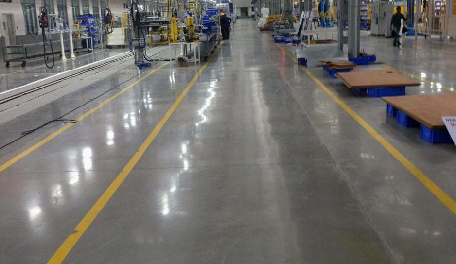 Polished industrial floor with yellow safety lines and machinery in a clean manufacturing facility.